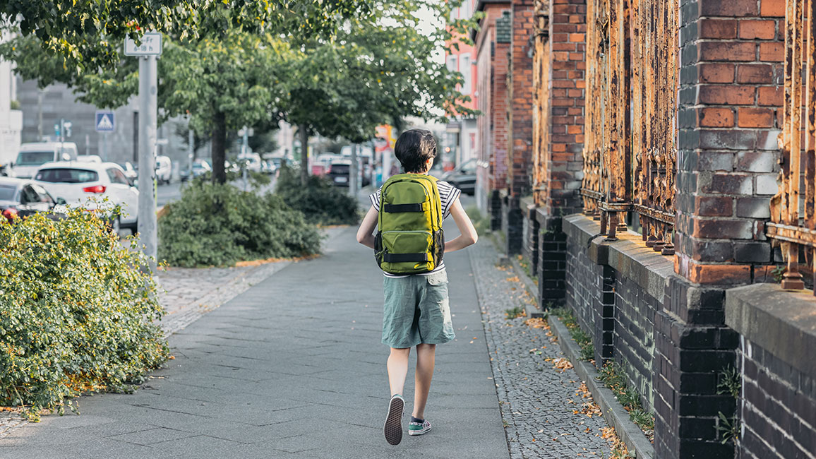 Mädchen mit Rucksack läuft Straße entlang